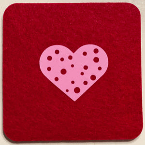 Closeup product image of a square shaped wool red drink coaster with a pink heart heat transfer design