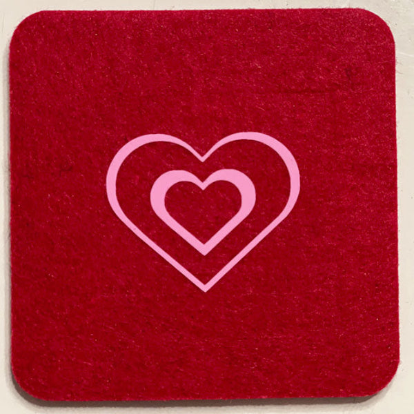 Closeup product image of a square shaped wool red drink coaster with a pink double heart heat transfer design