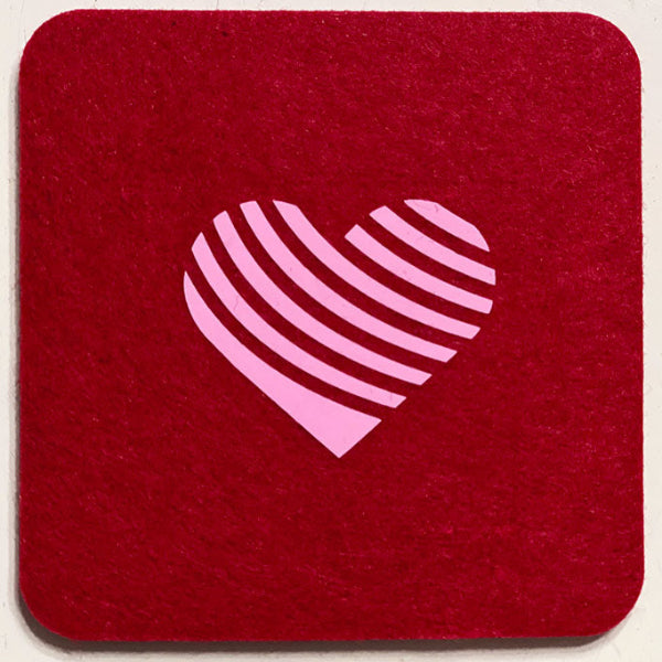 Closeup product image of a square shaped wool red drink coaster with a pink heart heat transfer design