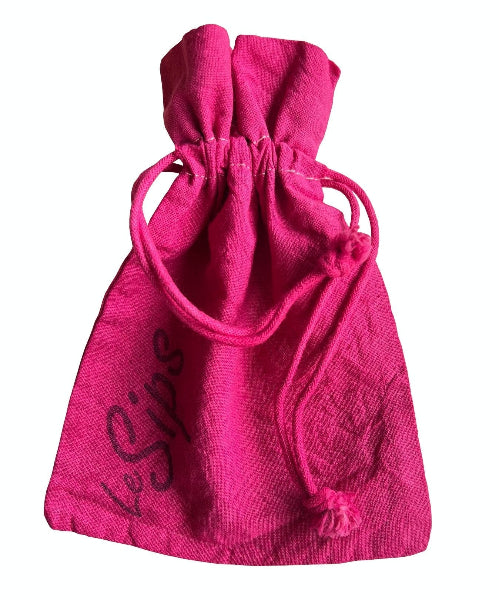 Closeup front view of a fuchsia pink colored hand dyed drawstring travel bag with the word LeSips stamp printed along the side