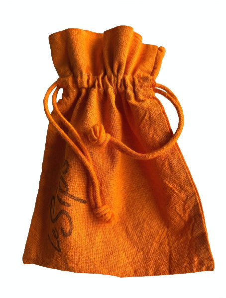 Closeup front view of a orange colored hand dyed drawstring travel bag with the word LeSips stamp printed along the side