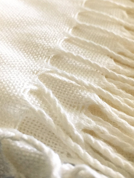 Closeup image of cream color bamboo pashmina scarf with fringe and detail of fabric weave