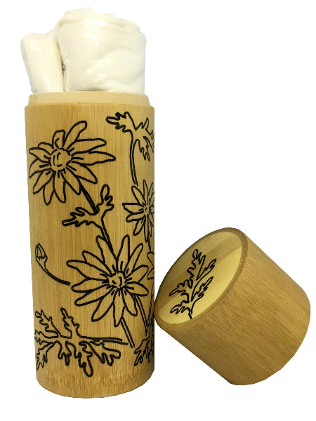 Closeup product image of a bamboo container with hand drawn floral design on the outside of the container and bamboo lid. Bamboo container has a cream colored rolled up bamboo scarf inside of it