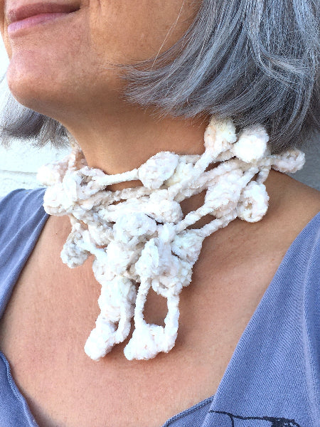 Closeup image of a woman wearing a grey t-shirt and a hand crocheted bobble chenille necklace