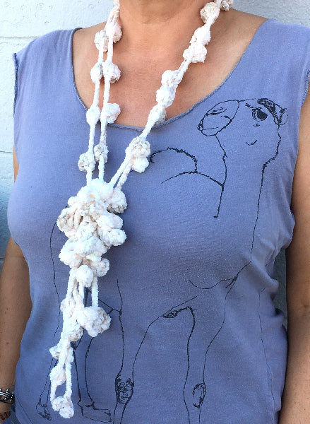 Closeup image of a woman wearing a grey graphic t-shirt and a hand crocheted bobble chenille necklace