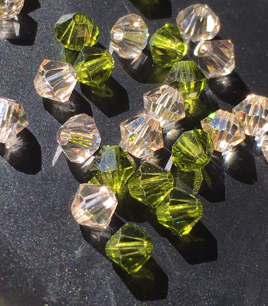 Closeup image of clear and green swarovski crystal beads laying on a black table