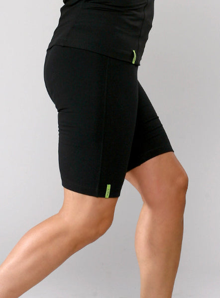 Closeup product image of a woman's waist and legs wearing black long activewear shorts