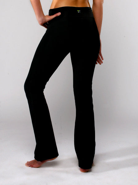 Back view of a woman from the waist down wearing black boot cut yoga pants with bare feet posing with hand on hip