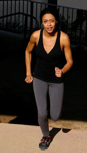 Image of a female athlete running up steps, wearing a black tank top and grey leggings