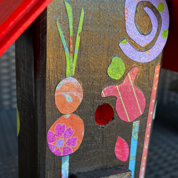 Closeup image of a metallic brown painted wooden decorative birdhouse with decoupaged floral designs