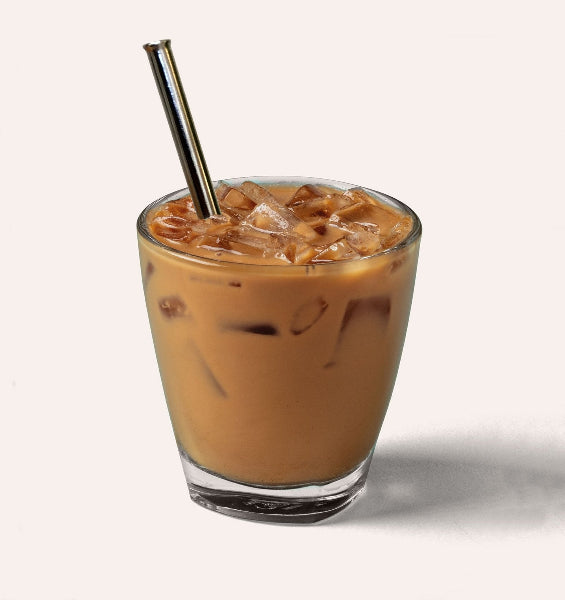 Closeup image of a clear glass with iced coffee drink and a stainless-steel drinking straw