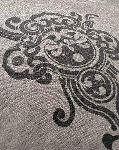 Closeup image of a grey heather t-shirt with a henna like graphic print design