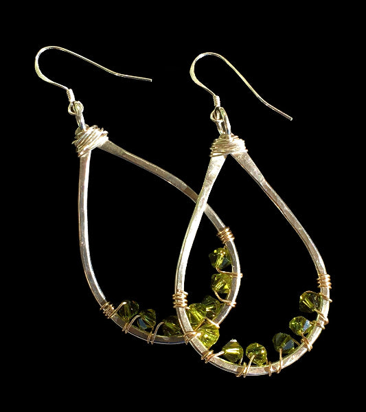 Image of a pair of hammered sterling silver teardrop earrings with gold wire wrap and swarovski crystals on a black background