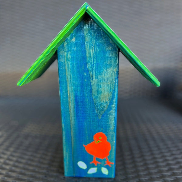 Closeup image of a hand painted blue decorative birdhouse with a green roof and an orange chick painted at the bottom