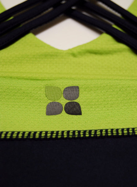 Closeup detail image of a yoga top with bright apple green mesh and a Yoga City logo and navy blue stitching