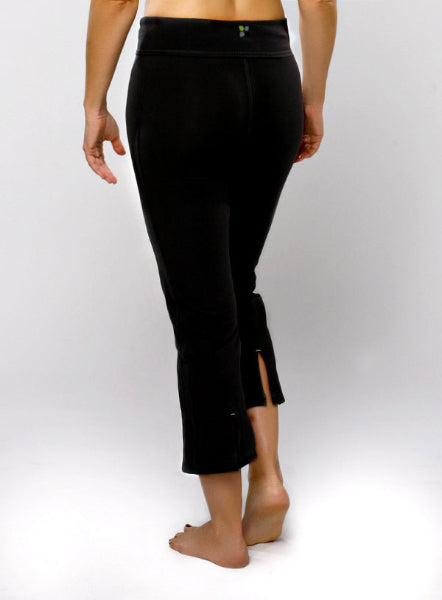 Back view of a woman from waist down wearing a pair of black cropped capri yoga pants with slit vent at the back leg