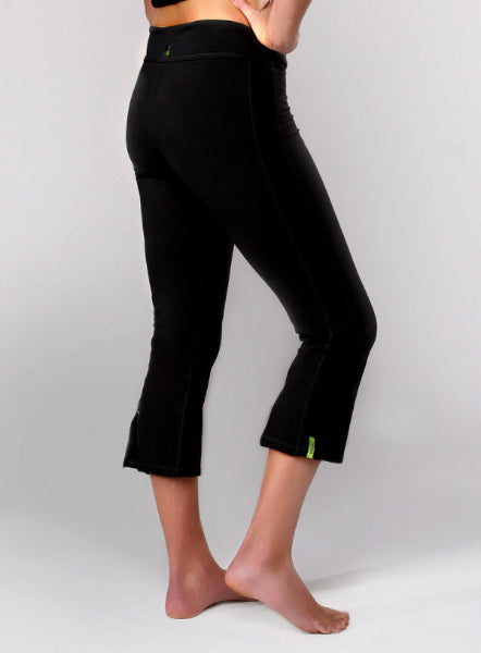 Product image of woman's body from waist down wearing black cropped capri yoga pants with back slits at the bottom hem