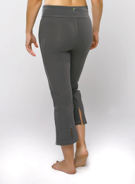 Back view image of a woman from waist down, wearing a pair of grey cropped yoga capri pants with vent slits at the bottom hems