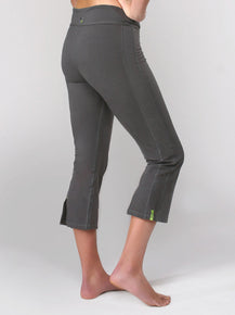 Product side view image of a woman from waist down, wearing grey yoga cropped capri pants with vents at the bottom hem and an adjustable waistband