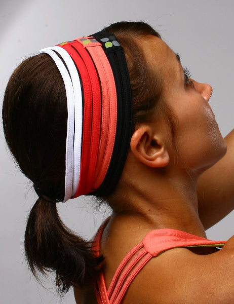 Side view of a woman's head with a ponytail wearing multiple headbands in white, red, coral and black