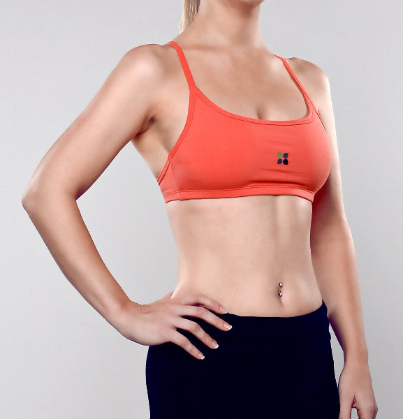 Closeup front view image of a woman wearing a coral orange color sport bra and black yoga pants